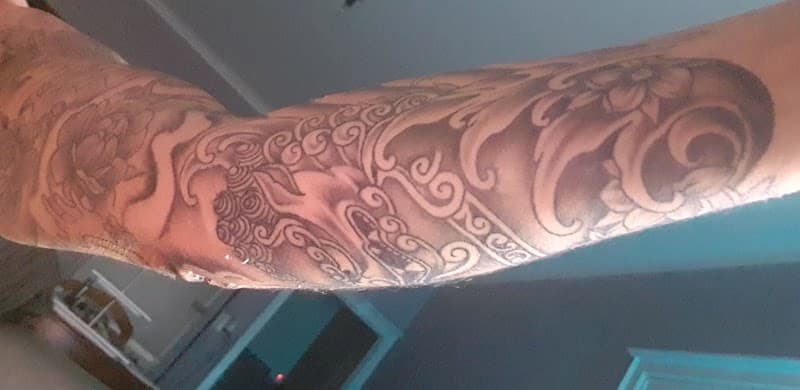 Grote Japanse tattoo met golven en bloemen op bovenarm.