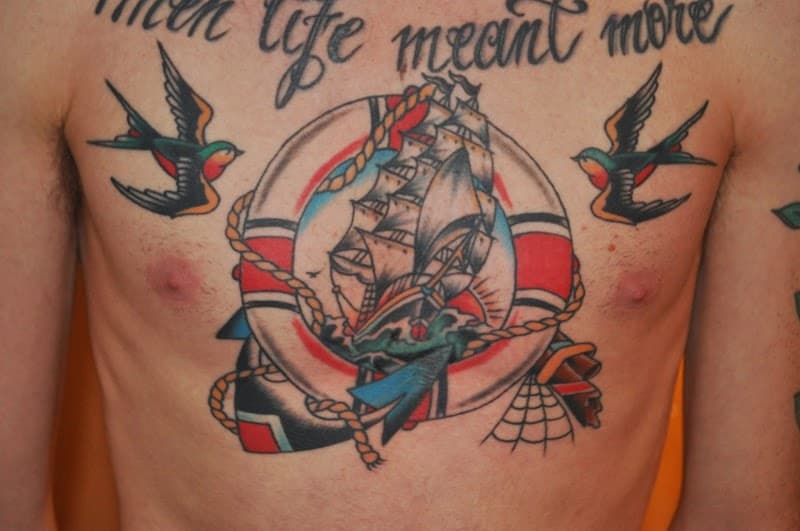 Traditionele borsttattoo met schip, reddingsboei, zwaluwen en tekst.