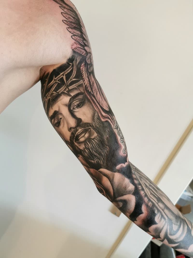 Realistisch portret van Jezus met doornenkroon op bovenarm.