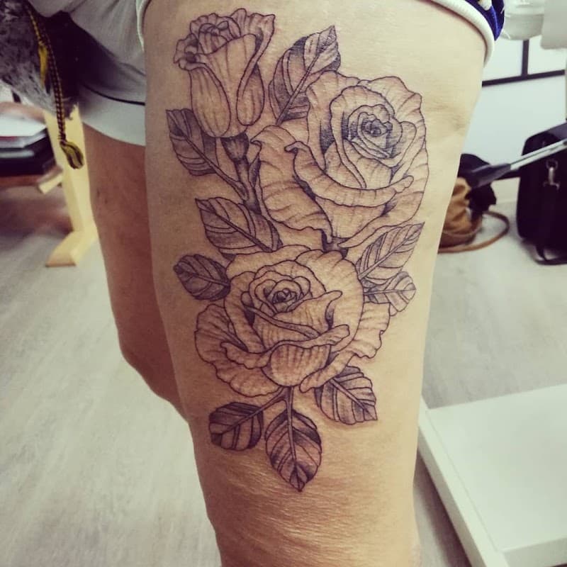 Grote fineline rozen tattoo op bovenbeen.