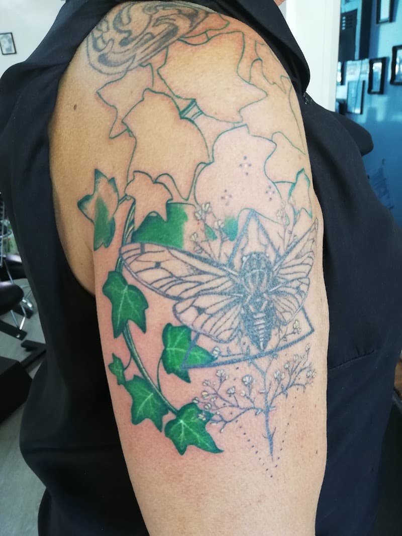 Cicade met geometrische vormen en groene klimopbladeren op de bovenarm.