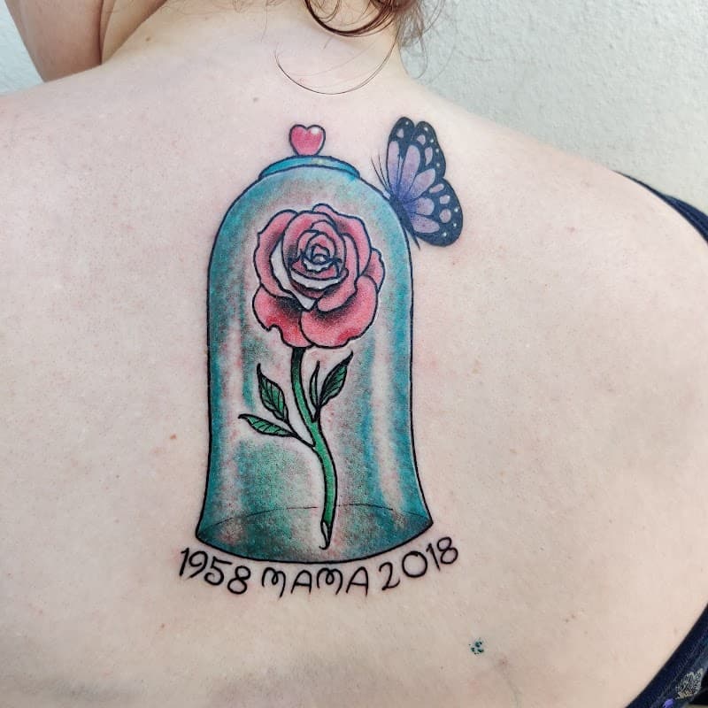 Kleurrijke roos in stolp met vlinder en '1958 MAMA 2018' tekst.