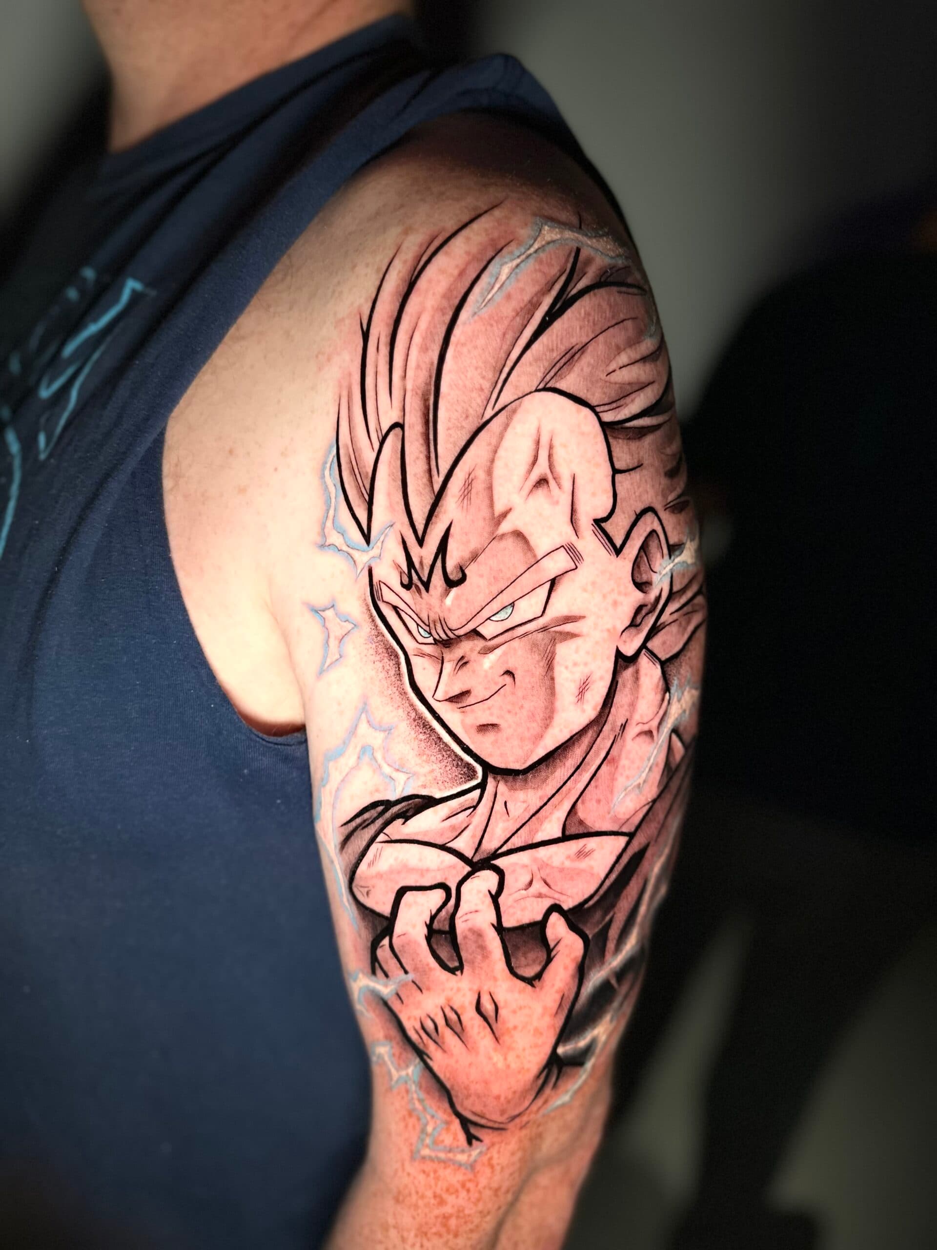 Illustratieve Majin Vegeta tattoo met blauwe bliksem op bovenarm.