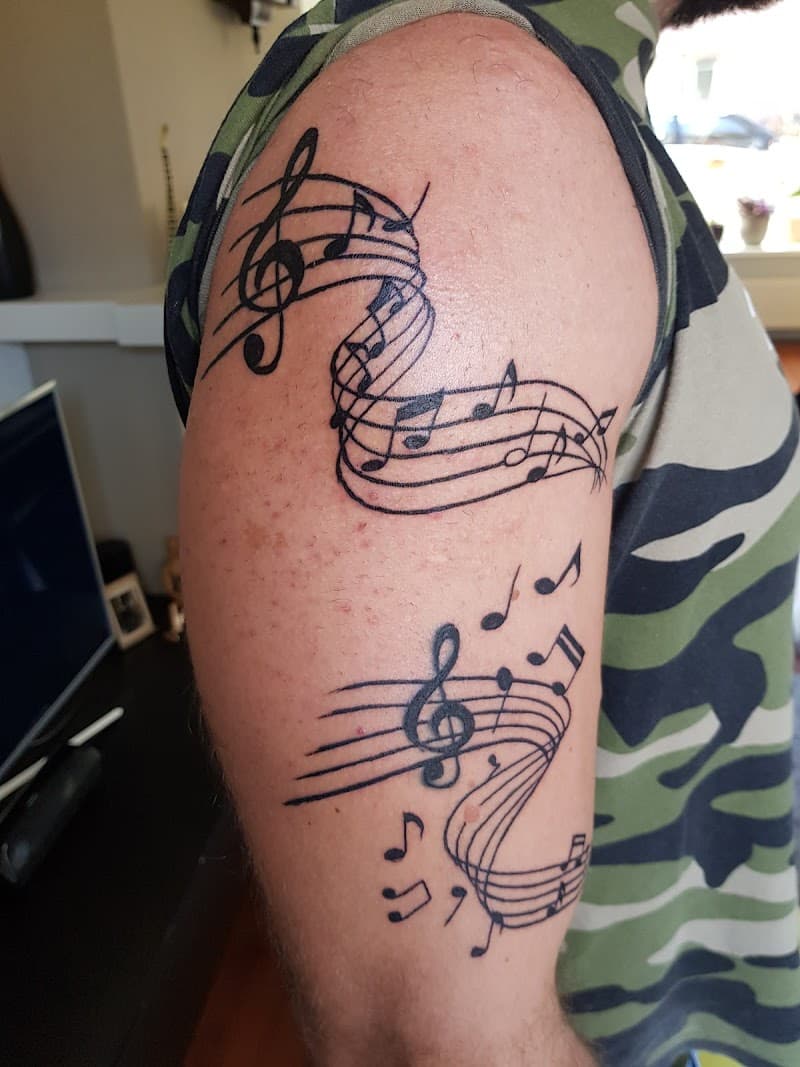 Twee muzieknotenbalken met solsleutels en noten op de bovenarm.