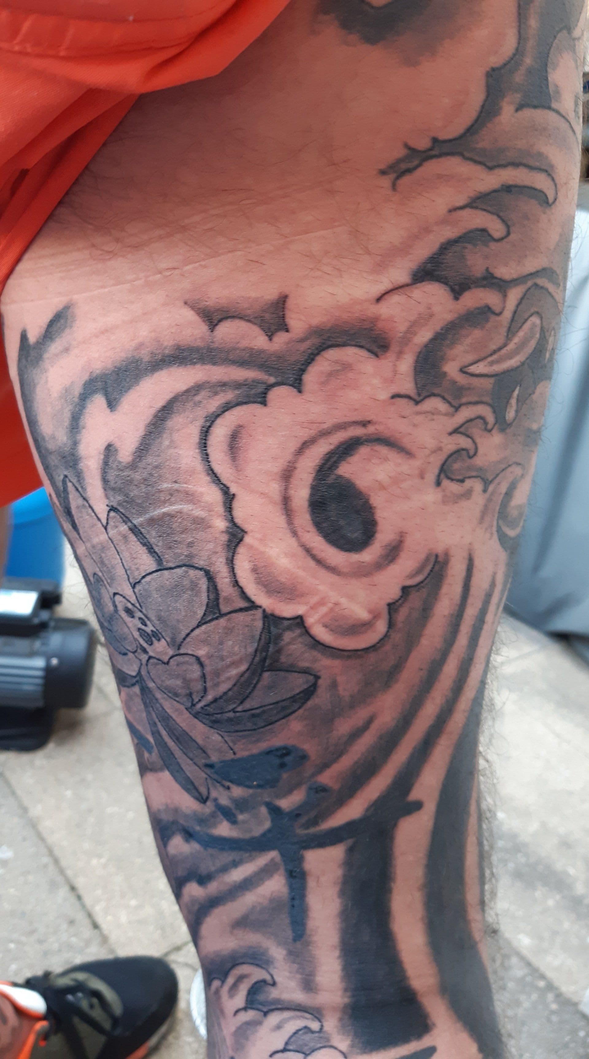 Zwart-wit Japanse stijl tattoo met lotus en golven op bovenbeen.