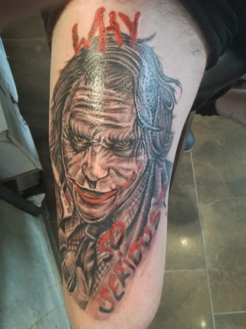 Realistische Joker tattoo met rode tekst "Why So Serious?" op bovenbeen.