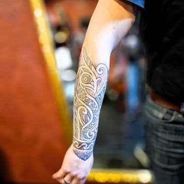 Polynesische stijl tattoo op onderarm met tribale patronen.