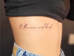 Fineline tekst 'to the moon and back' op de ribben.