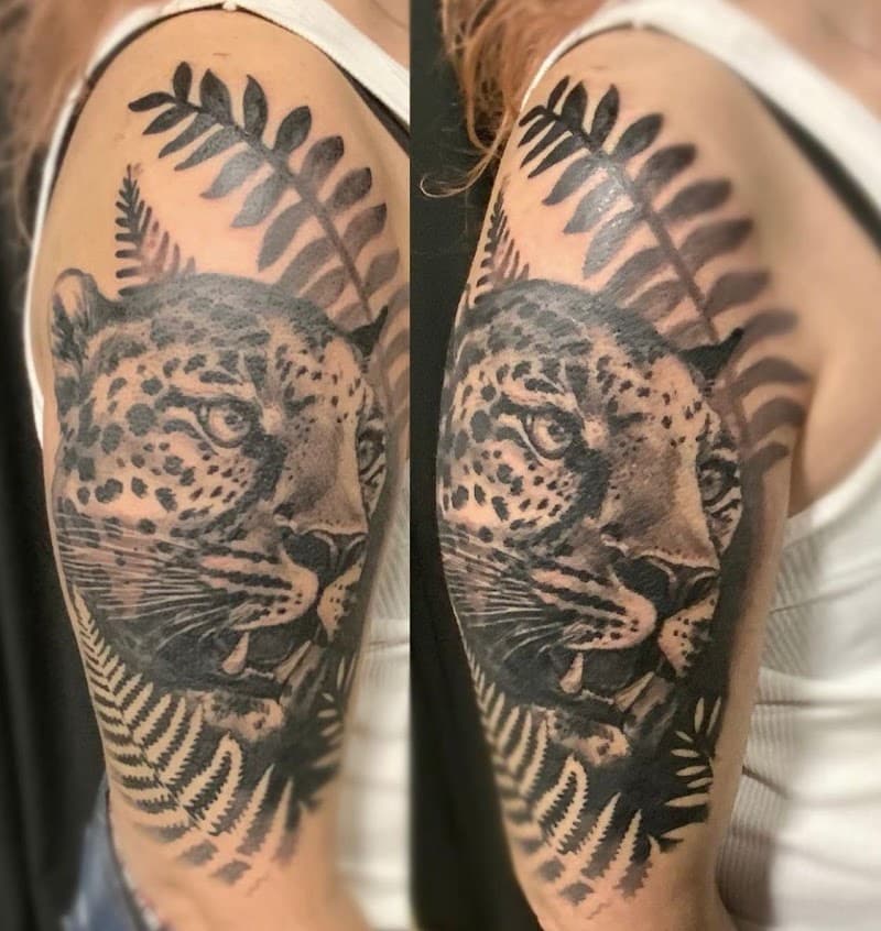 Realistische luipaardkop met varens op bovenarm.