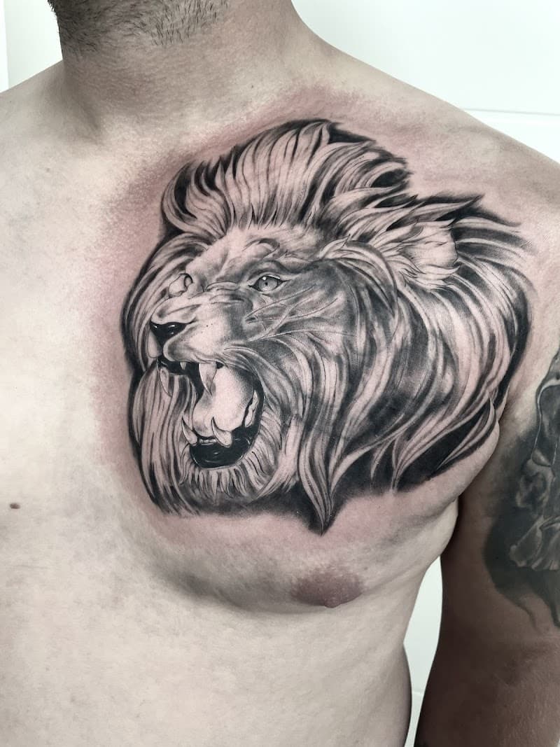 Realistische zwart-wit leeuwenkop tattoo op de borst.