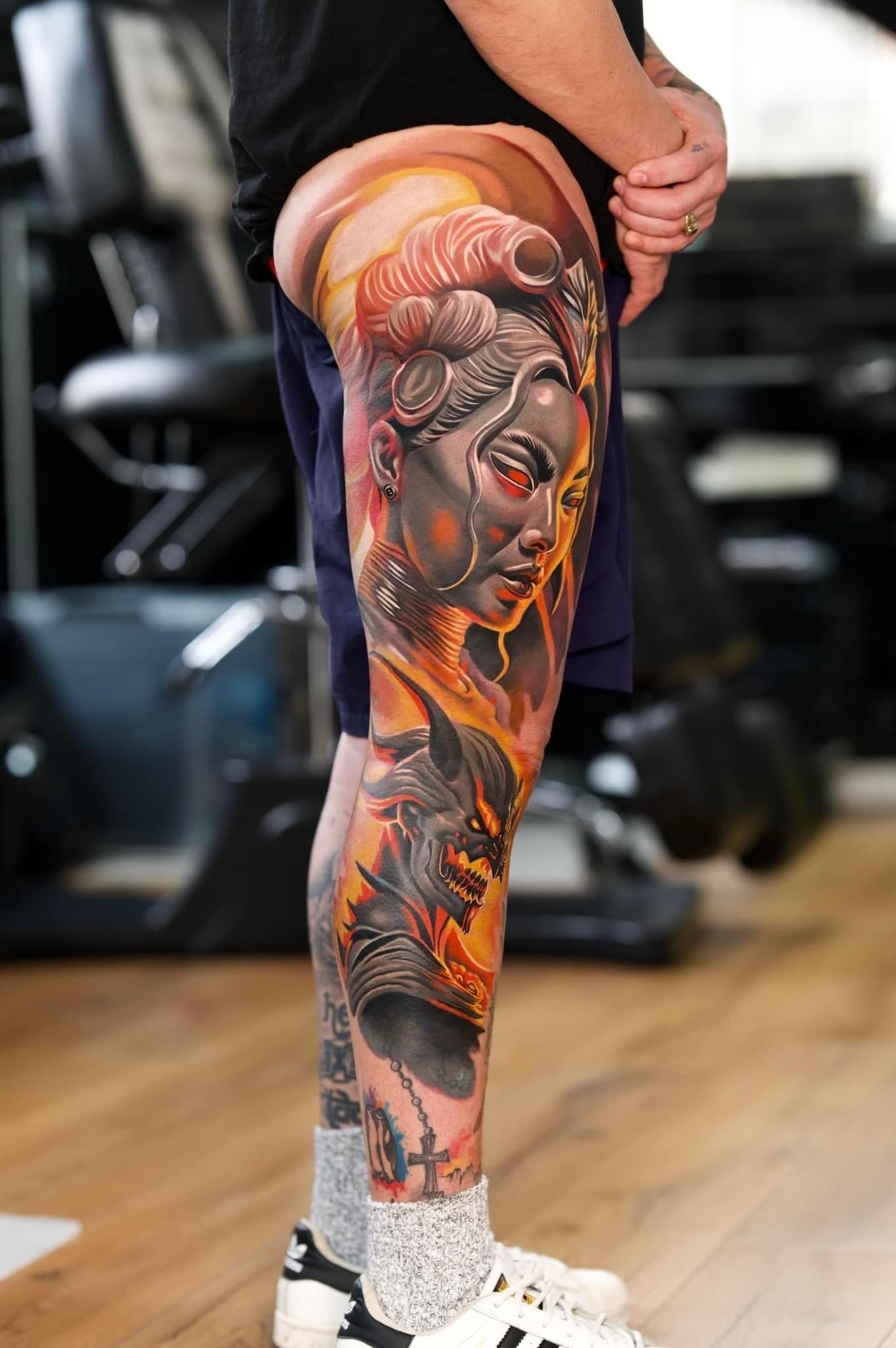 Grote, kleurrijke tattoo van een vrouw en een demon op het hele been.