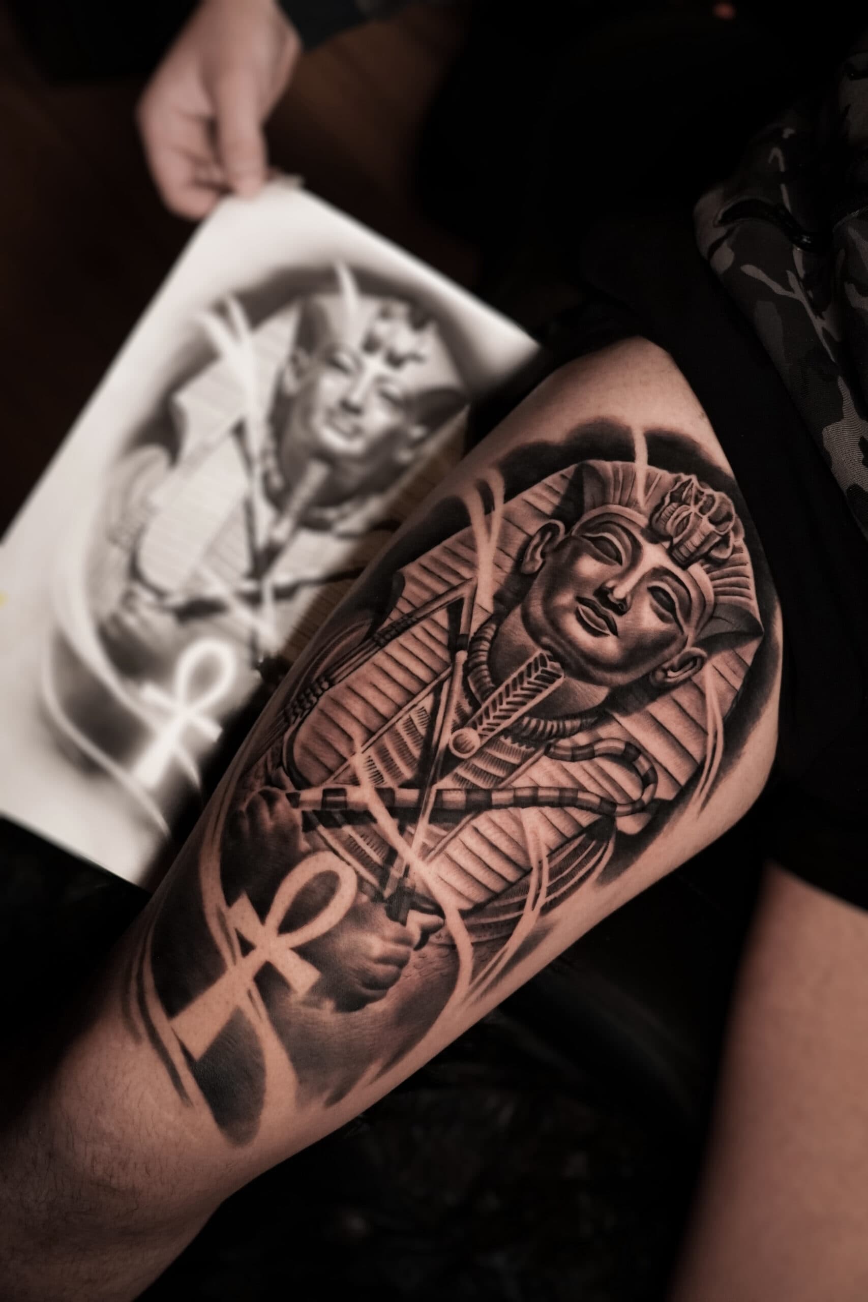 Realistische zwart-wit tattoo van een Egyptische farao en Ankh op het bovenbeen.