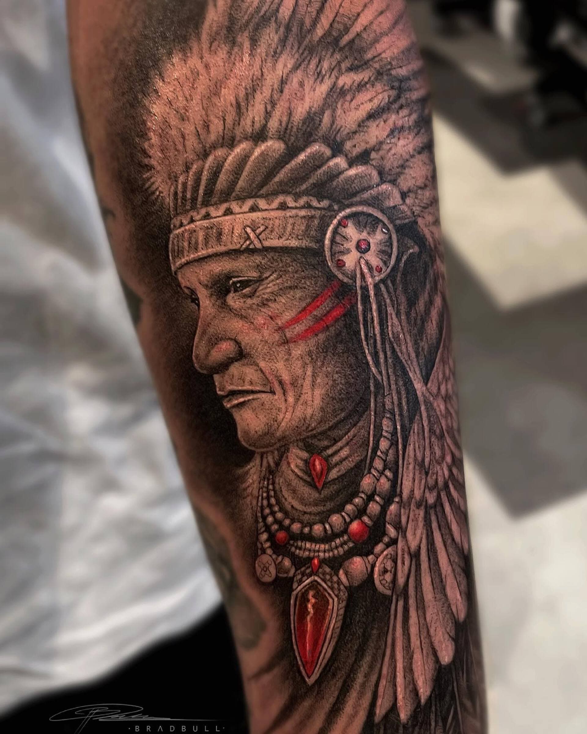 Realistisch portret van een Indiaans opperhoofd met verentooi en rode details.