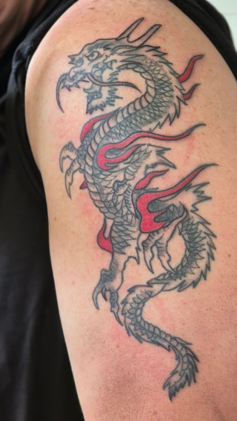 Zwart-grijze draak met rode vlammen op bovenarm