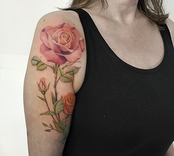 Realistische roze en oranje rozen op bovenarm.