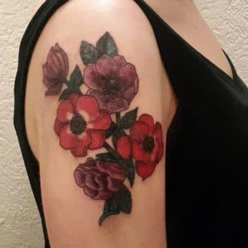 Kleurrijke bloemen (rood/paars) met bladeren op bovenarm