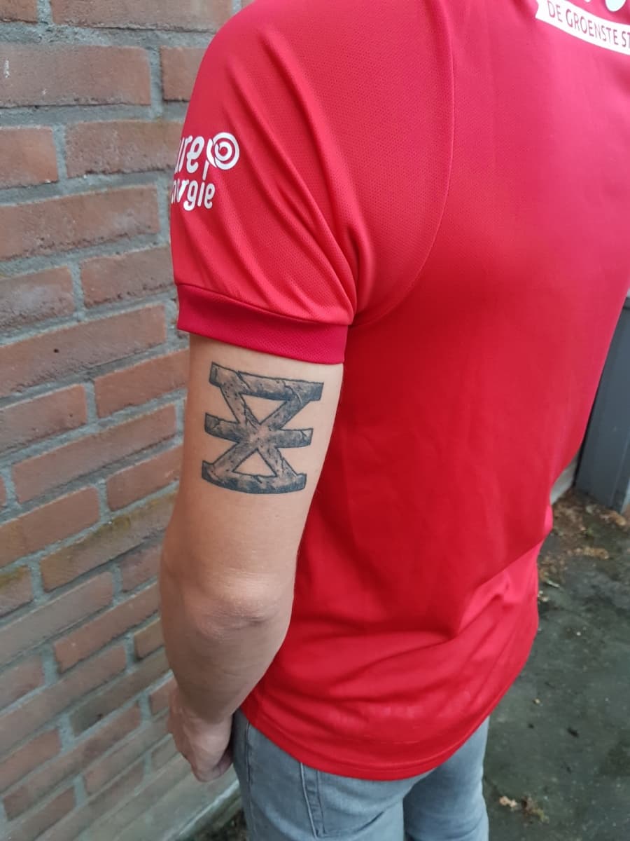 Zwart-wit symbool tattoo op de bovenarm.